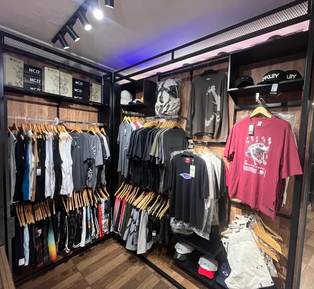 O canto da Oakley na loja: camisetas, bermudas e bonés Oakley na parede de madeira